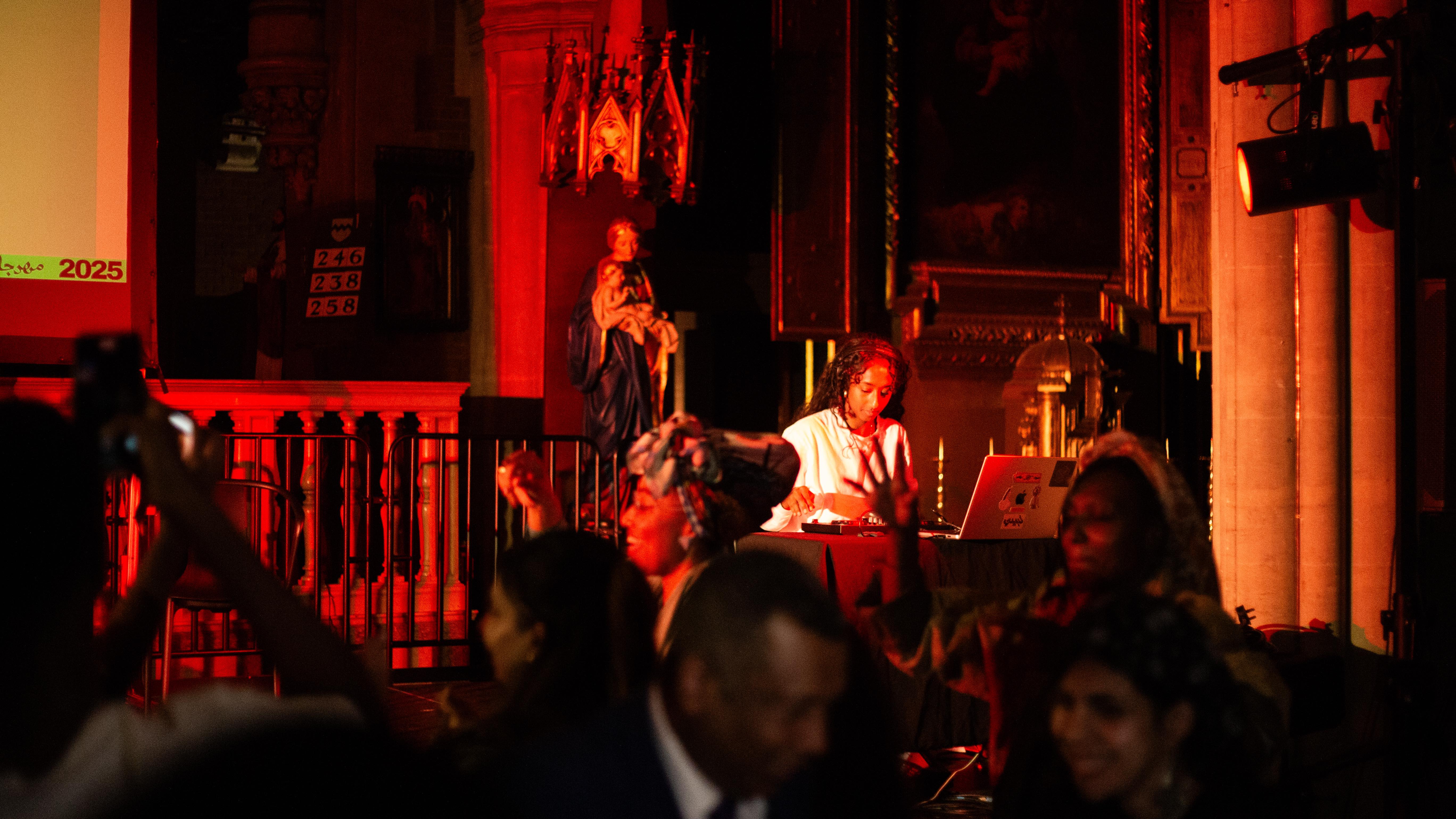 A photo of Tabideee DJing in a church. In the foreground, people are dancing and laughing.
